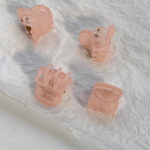 Close-up of four mini translucent pink glitter hair claws for styling side bangs and hair