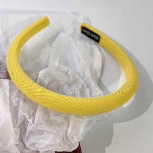 Gros plan détaillé du serre-tête en maille jaune avec étiquette fait main sur fond blanc