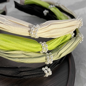 Close-up of pleated satin headbands with faux pearl accents in multiple soft colors