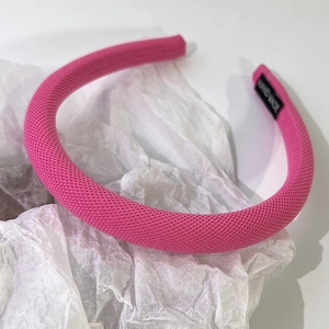 Détail de l'étiquette Hand Made sur un serre-tête en éponge tressée rose vif