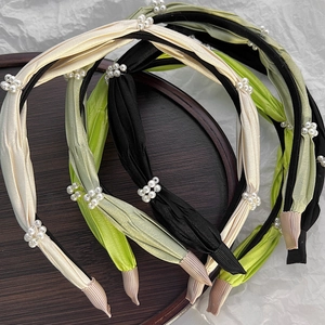 Detailed view of ruched fabric headbands with elegant pearl clusters in three colors