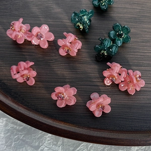 Dettaglio delle mini mollette per capelli a fiore con strass lucidi in rosa e verde