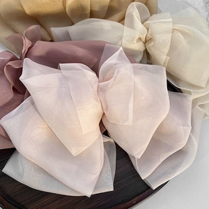 Macro shot of large multi-layer organza bow hair clips in pastel colors on wooden tray
