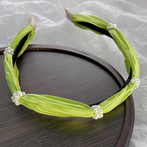 Detailed view of pleated green satin headband decorated with elegant white pearl clusters