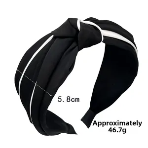 Detail of a 5.8cm wide vintage knotted headband in black matte fabric with white piping