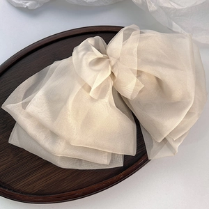 Detail of elegant champagne oversized chiffon bow hair clip on a vintage wooden tray
