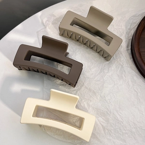 Macro shot of large matte rectangular hair claws in khaki, coffee, and creamy white tones