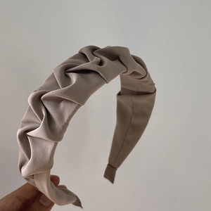 Detail shot of the pleated fabric texture on a wide-brimmed vintage style headband
