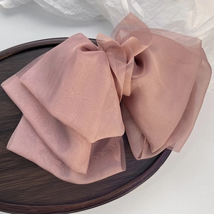Macro detail of dusty pink organza oversized bow hair clip on a wooden display tray