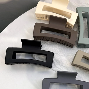 Macro detail of matte rectangular hollow hair claws in various elegant earth tones