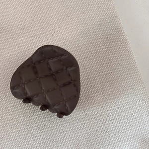 Detail view of dark brown matte hair claw clip with elegant quilted texture on fabric