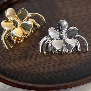 Dettaglio di eleganti fermagli per capelli a fiore in lega oro e argento con finitura lucida
