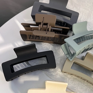 Close-up of matte rectangular hair claws in various neutral colors on a white texture