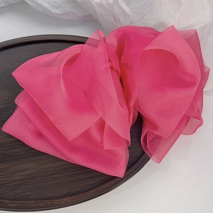Detailed view of layered bright pink chiffon fabric in a wooden tray with soft textures