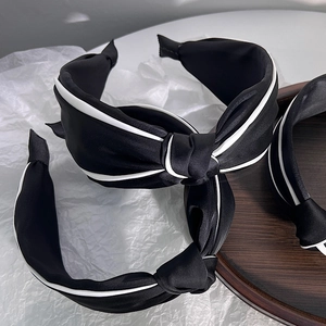 Three-piece black silk headband set with white piping trim and knot detail on a tray