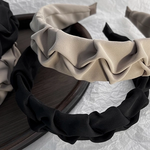 Detail of pleated fabric headbands in black and khaki colors on a wooden tray