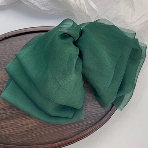 Detail of dark green oversized chiffon bow hair clip with layered pleated texture