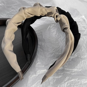 Close-up of pleated fabric headbands in black and beige with soft wrinkled texture