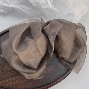 Detail of a large brown organza hair clip with a layered bow design on a vintage tray