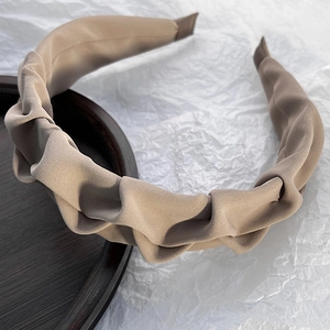 Close-up of khaki pleated headband showing elegant fabric texture and wide retro design