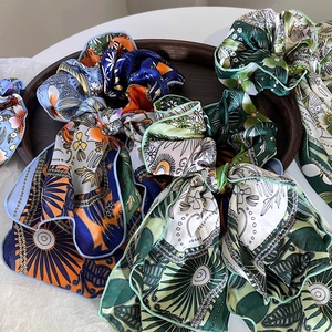Floral silk scrunchies with long streamers in vintage patterns on a wooden tray
