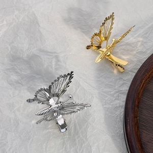 Elegant hollow butterfly hair clips in gold and silver alloy on textured white paper