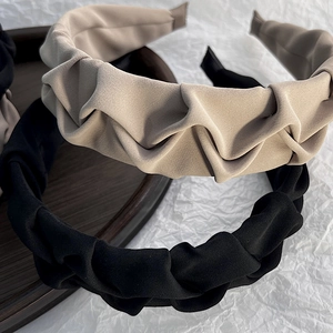 Close-up of matte pleated headbands in black and khaki colors with cloud-like textures