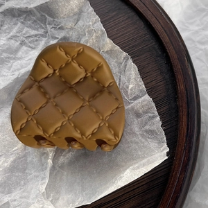 Macro view of matte caramel hair claw clip featuring detailed quilted lattice patterns
