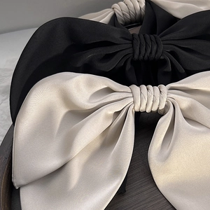 Detailed macro view of black and beige satin bow hair clips with elegant silk texture