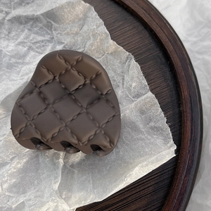 Detailed view of matte brown quilted hair claw clip with cross-hatch texture