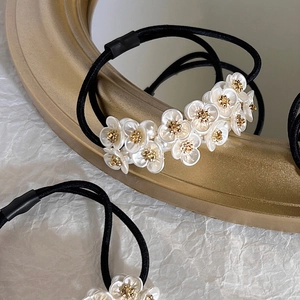 Close-up of pearl flower hair tie with golden center on white textured background