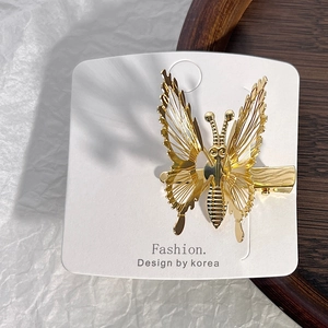 Close-up of golden hollow metal butterfly hair clip with intricate wire craft detail
