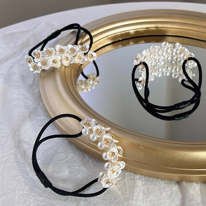 Close-up of elegant white pearl floral hair ties on a vintage gold mirror surface