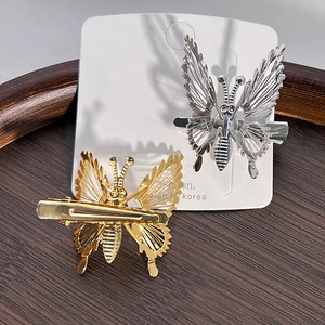 Detail of hollow metal butterfly hair clips in gold and silver on white card