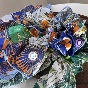 Close-up of bohemian floral chiffon scrunchie with streamers on vintage wooden tray