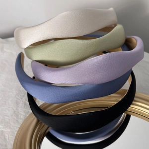 Five assorted colors of padded satin sponge headbands stacked on a golden mirror tray