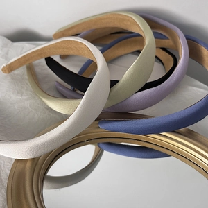 Detailed close-up of padded fabric headbands in various solid Morandi colors displayed on gold mirror