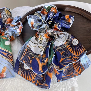 Detail view of Bohemian print chiffon hair scrunchie with streamers on wooden tray