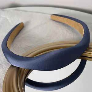Detail of navy blue padded satin headband with non-slip khaki velvet lining on a mirror