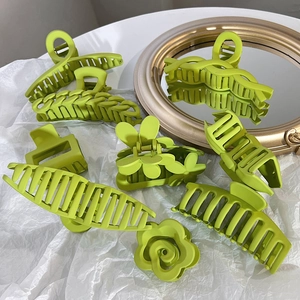 Variety of bright green matte hair claws with cloud and chain designs on a mirror