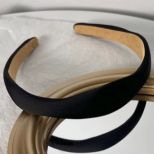 Detail of black padded satin headband with non-slip lining on a gold mirror surface
