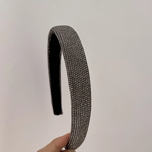Primo piano di un cerchietto largo con strass grigio scuro densamente incastonati