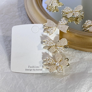 Detailed shot of pearl butterfly and flower hair clips in elegant golden alloy finish