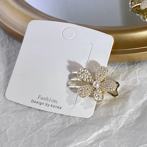 Macro shot of pearl flower hair clip on display card with gold alloy finish