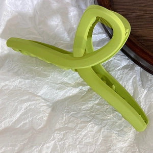 Close-up of lime green matte hair claw clip with a twisted geometric structure