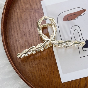 Dettaglio di una pinza per capelli dorata con perle incastonate su vassoio in legno