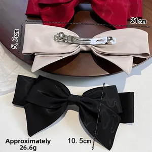 Macro detail of large satin bow hair clips with metal spring mechanism and size specs