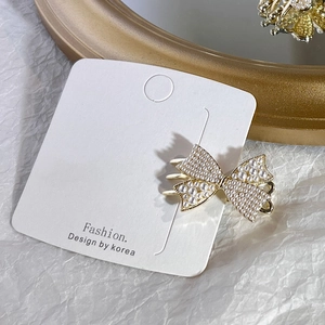 Detailed view of butterfly bow hair clip with faux pearls and golden alloy base