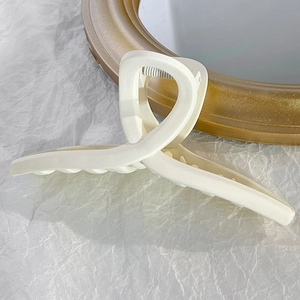 Détail de la pince à cheveux crème mate au design torsadé sur papier texturé