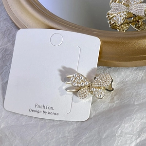 Detailed view of a gold butterfly hair clip with pearl embellishments on a display card